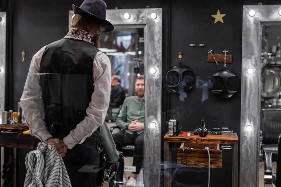 A barber seen from behind, facing the mirror wall