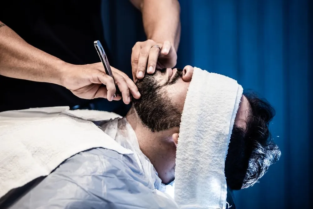 A hot towel laid over a customer's face before a shave