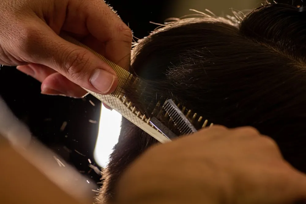 A barber shaping a beard line with a razor